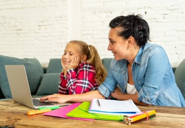 Genç kız evde ebeveynlik ödev ve eğitim kavramı içinde kanepede oturan laptop ve okul kitapları ile ödev yardım Anne
