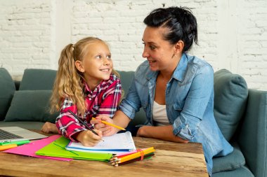 Güzel annem evde ödev ebeveynlik ve eğitim kavramı ödev yapmak onun genç sarışın sevimli tatlı kız yardım.