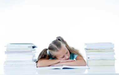 Exhausted sweet cute blonde girl sleeping on a pile of schoolbooks after being studying hard isolated on a withe background in too much learning pressure at school and education concept