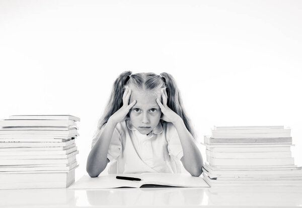 Sad and tired cute schoolgirl with blond hair sitting in stress doing homework overwhelm with too much study and textbooks in children education academic performance ans school systems concept