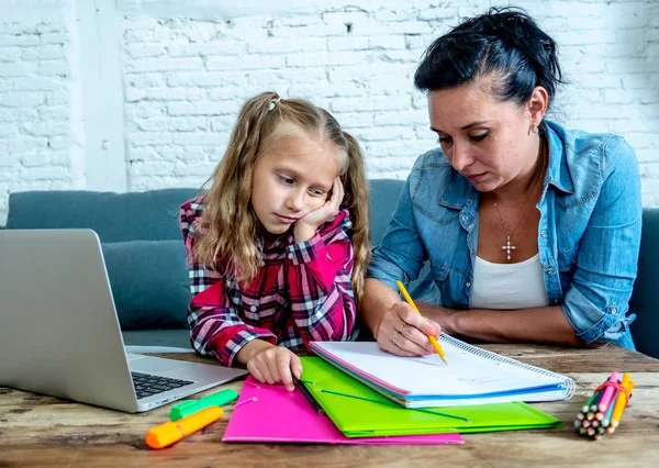 Mother becoming frustrated with daughter whilst doing homework sitting on sofa At home in learning difficulties homework parenting and education concept
