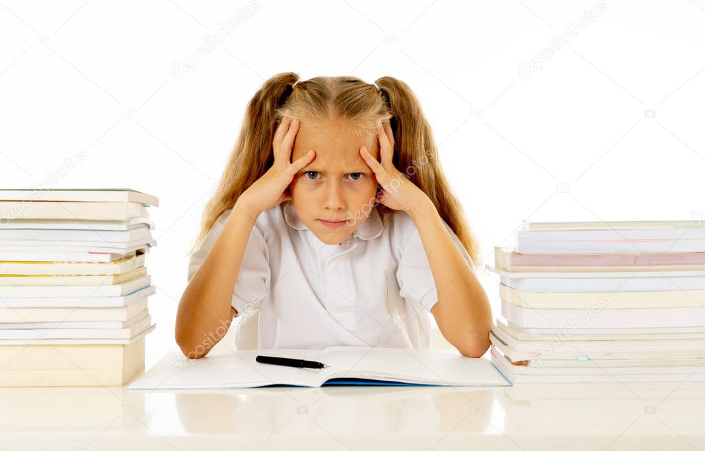 Sad and tired cute schoolgirl with blond hair sitting in stress doing homework overwhelm with too much study and textbooks in children education academic performance ans school systems concept