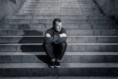 Lost ın depresyon zemin beton merdiven duygusal acı yalnızlık üzüntü zihinsel sağlık kavramı grunge aydınlatmada yalnız oturan genç umutsuz işsiz adam rahat kıyafetler içinde terk.