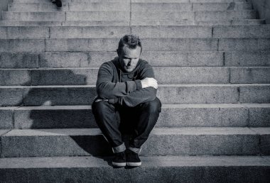 Lost ın depresyon zemin beton merdiven duygusal acı yalnızlık üzüntü zihinsel sağlık kavramı grunge aydınlatmada yalnız oturan genç umutsuz işsiz adam rahat kıyafetler içinde terk.