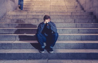 Lost ın depresyon zemin beton merdiven duygusal acı yalnızlık üzüntü zihinsel sağlık kavramı grunge aydınlatmada yalnız oturan genç umutsuz işsiz adam rahat kıyafetler içinde terk.