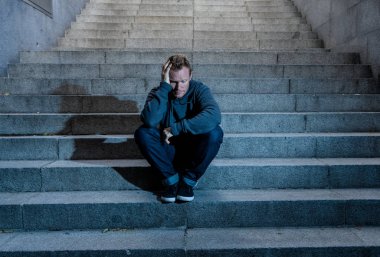 Lost ın depresyon zemin beton merdiven duygusal acı yalnızlık üzüntü zihinsel sağlık kavramı grunge aydınlatmada yalnız oturan genç umutsuz işsiz adam rahat kıyafetler içinde terk.