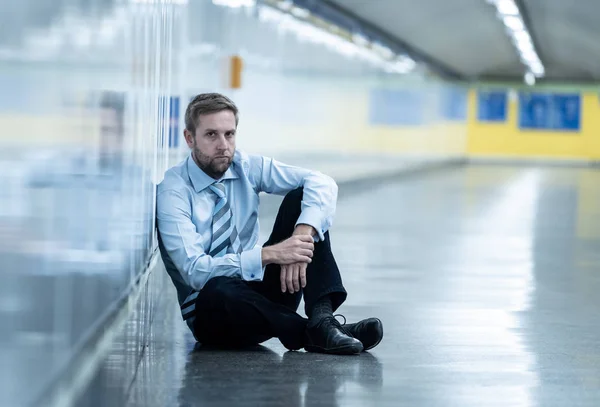 Young jobless business man suffering depression sitting on ground street underground leaning on wall alone looking desperate in Emotional pain Mental health Unemployment and Human emotions concept.