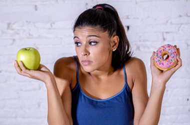 Güzel genç kadın sağlıklı sağlıksız gıda, elma ve halka arasında seçim yapmak zorunda cazip detoks yeme, kalori ve diyet kavramı.