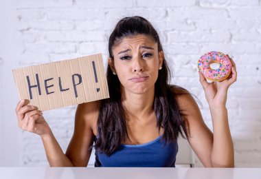 Young worried latin woman feeling tempted and guilty wanting to eat chocolate and donuts asking for help in diet calories sugar addiction nutrition and lifestyle concept. clipart