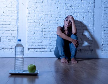 Umutsuz diyet genç kadın deli diyet irade ve beslenme sembolü olarak bir elma meyve ve su üzgün seyir yerde oturuyordu bozukluğu.
