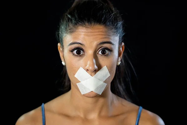 Attractive scared woman with taped mouth making in Silence Abuse Censorship Me too and Freedom of speech Concept Isolated on black background.