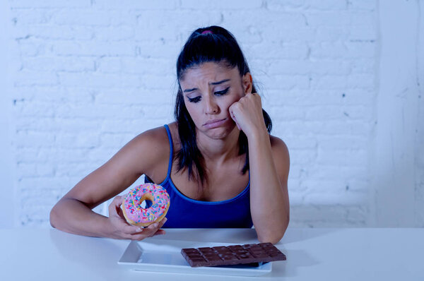 Голодная красивая молодая женщина несчастливо жаждет сладкий шоколад и пончики и не может есть в диете Потеря веса Сахарная зависимость Диабетическая и нездоровая концепция здорового питания
.