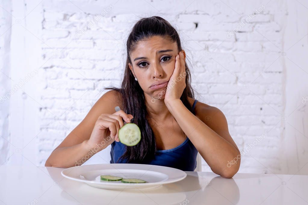 Portrait o f young attractive woman feeling sad and bored with diet not wanting to eat vegetables or healthy food in Dieting Eating Disorders and weight loss concept.
