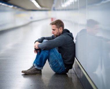 Üzgün genç adam ağlayan acı depresyon stres zemin sokak Metro'ya eğilerek duvar ruhsal bozukluk duygusal ağrı bağımlılığı yalnız ve işsizlik kavramı üzerinde umutsuz seyir üzerinde oturan.