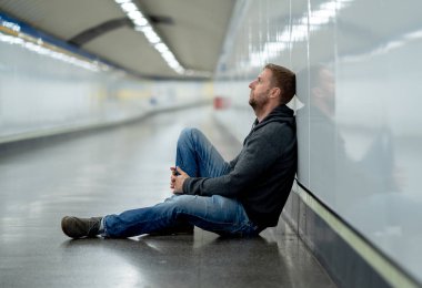 Üzgün genç adam ağlayan acı depresyon stres zemin sokak Metro'ya eğilerek duvar ruhsal bozukluk duygusal ağrı bağımlılığı yalnız ve işsizlik kavramı üzerinde umutsuz seyir üzerinde oturan.