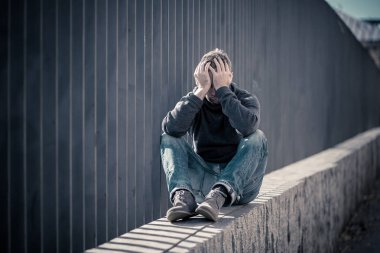 Genç çekici adam acı depresyon stres tek başına oturmak ve üzücü duygu endişeli ve işsizlik ruh sağlığı uyuşturucu ve alkol bağımlılığı kavram yalnız sokakta.
