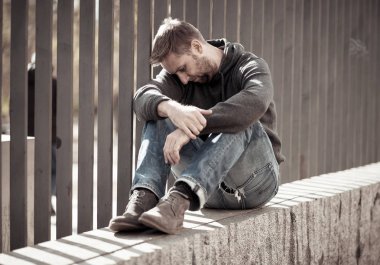 Genç çekici adam acı depresyon stres tek başına oturmak ve üzücü duygu endişeli ve işsizlik ruh sağlığı uyuşturucu ve alkol bağımlılığı kavram yalnız sokakta.