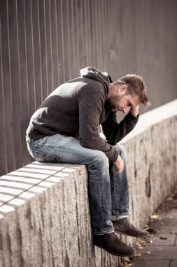 Genç çekici adam acı depresyon stres tek başına oturmak ve üzücü duygu endişeli ve işsizlik ruh sağlığı uyuşturucu ve alkol bağımlılığı kavram yalnız sokakta.