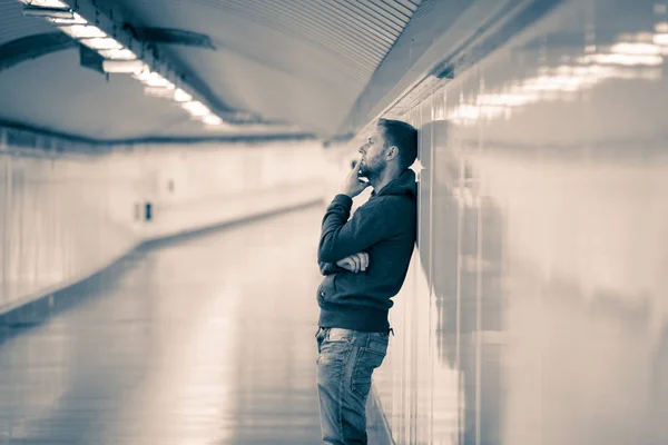 Sad jobless young man crying suffering depression stress sitting on ground street subway tunnel looking desperate leaning on wall alone in Mental disorder Emotional pain Drug abuse and Alcoholism.