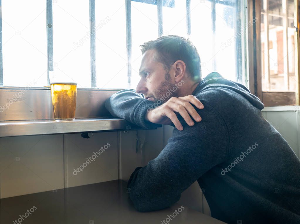 Portrait of a attractive man drinking beer in a bar pub feeling depressed unhappy and lonely in Alcohol Use Abuse Depression and mental health concept.