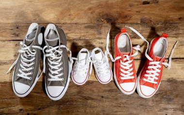 Lastikbotlar spor ayakkabı ayakkabı baba anne ve oğlu kızı ailesinin tatlı ev beraberlik mutlu aile ebeveynlik ve yaşam tarzı kavramı farklı boyutlarda vintage ahşap zemin üzerinde kavramsal görüntü.