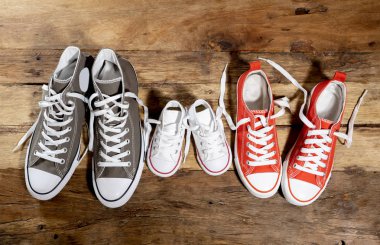 Lastikbotlar spor ayakkabı ayakkabı baba anne ve oğlu kızı ailesinin tatlı ev beraberlik mutlu aile ebeveynlik ve yaşam tarzı kavramı farklı boyutlarda vintage ahşap zemin üzerinde kavramsal görüntü.