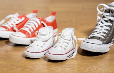 Lastikbotlar spor ayakkabı ayakkabı baba anne ve oğlu kızı aile tatlı ev beraberlik mutlu aile ebeveynlik farklı boyutlarda ahşap zemin üzerinde ve bir bebek kavram bekliyor kavramsal görüntü.