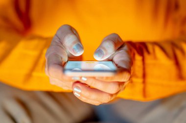 Online oynarken ve metin renkli bir arka plan ile akıllı telefon üzerinden ekran telefon bağımlılığı Internet oyun bağlantısı ve yeni teknoloji ışık göndererek genç veya yetişkin kadın kapatmak.