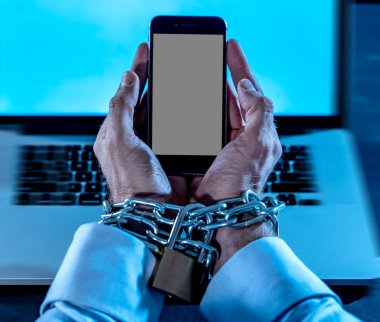 Genç adam bağlı ve akıllı bilek üzerinde asma kilit ile demir metalik zinciriyle kilitli cep telefonu eller bond bağımlısı telefon internet ve sosyal medya bağımlılık ve Teknoloji kurbanı kavramı köle.