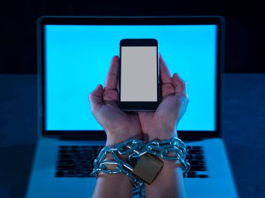 Genç adam bağlı ve akıllı bilek üzerinde asma kilit ile demir metalik zinciriyle kilitli cep telefonu eller bond bağımlısı telefon internet ve sosyal medya bağımlılık ve Teknoloji kurbanı kavramı köle.