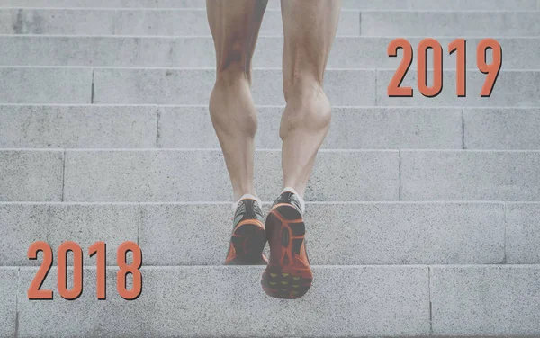 Conceptual image of strong athletic legs with ripped calf muscle of sport man running up from 2018 to 2019 on urban stairs in step towards and reach your goals this new year and Fitness Goals concept.