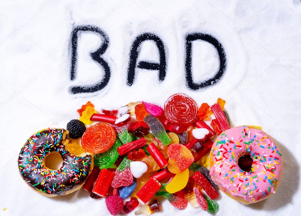 Colorful selection of sweets candies and treats with word Bad written on white sugar in sugar in children diet causes Health problems Nutrition Obesity Diabetes Dental care and Sugar addiction.