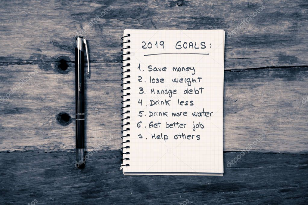 Top View 2019 New year resolutions list with plans for new life happy face written on notepad and pen on Vintage table in challenges Dreams and Goals for happiness Aspiration and Motivation Concept.