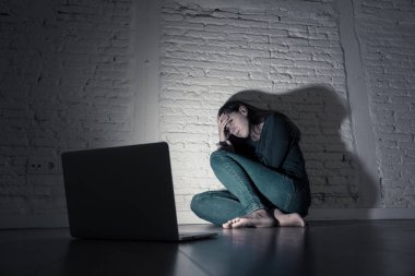 Sad and scared female Young woman with computer laptop suffering cyberbullying and harassment being online abused by stalker or gossip feeling desperate and humiliated in cyber bullying concept. clipart