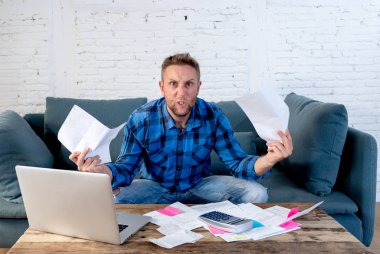 Vergi hesaplama faturaları giderleri ve eve sayma ve iş mali borçları ve yerli faturaları ve mali sorunlar kavramı kapalı ödeme evde kanepede oturan adam vurguladı ve endişeli.