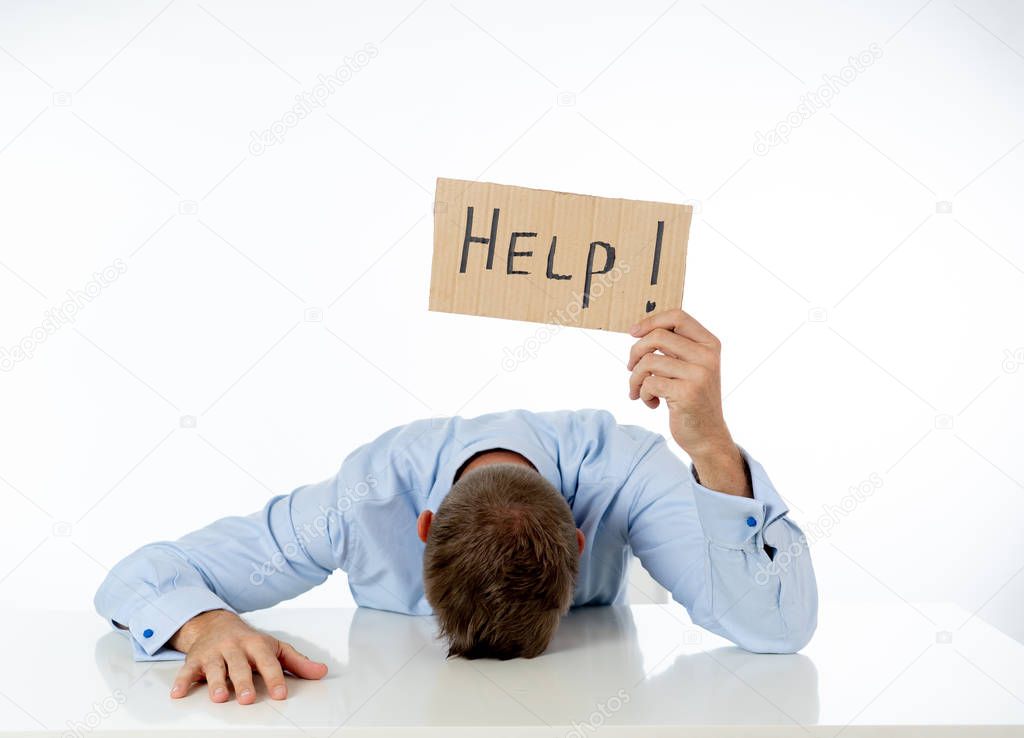 Young attractive frustrated and tired caucasian businessman holding help sign message exhausted and sad under pressure and stress isolated on white in unemployment depression and overwork concept.