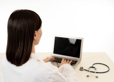 Bilgisayar laptop beyaz arka planda sağlık tıbbi teknoloji sigorta ve online tanı izole klinik Office online tedavi için çalışma çekici kadın doktorun arkadan görünüm.