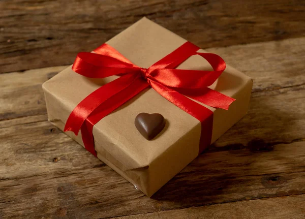 Valentines day gift box with red and chocolate heart on wooden background vintage style. Top view for Happy Valentines day decoration, wedding, anniversary and love celebration greeting card concept.