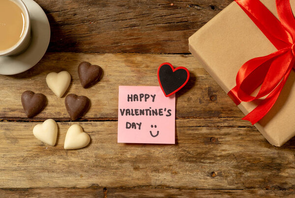 Композиция Валентины из подарка, шоколадного сердца в форме сердца, кофе и записки ко Дню святого Валентина, написанной по почте в винтажном стиле деревянного стола на фоне концепции празднования любви
.
