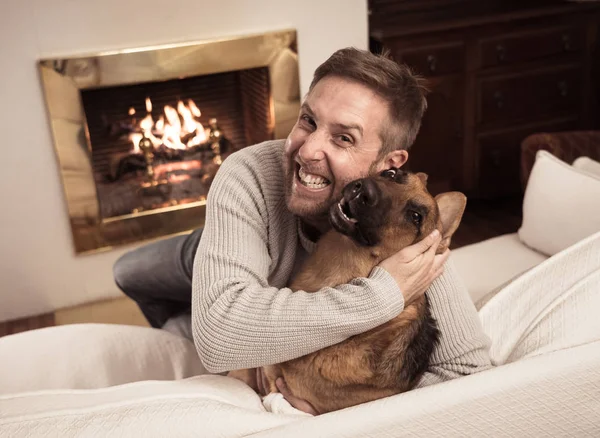 Beautiful portrait of smiling man hugging dog german shepherd playing together in front of fireplace at cozy home in winter day in happiness Friendship Love Companionship and benefits of pets animals.