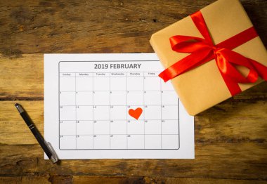 Kavramsal görüntü 2019 Şubat takvimi bir kalp 14 inci ve rustik vintage üzerinde kırmızı kurdele ile sarılmış mevcut Hediyelik Sevgililer günü tarihi saint için hazır masa ve aşk kutlama kavramı.