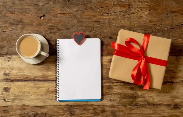 Beautiful Valentines composition of gift, chocolate heart shaped, coffee and noted pad with blank paper space for text in Happy Valentines, Mothers and fathers day and love celebration concept.