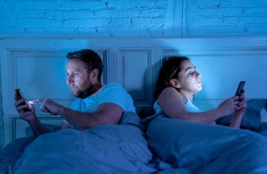 Teknoloji bağımlılığı birbirlerine ilgisizlik ve ilişki sorunları ve mobil internet bağımlılığı karanlıkta gece geç saatlerde akıllı telefonlarını kullanarak yatakta yatan öfke görmezden tarafından etkilenen çift.
