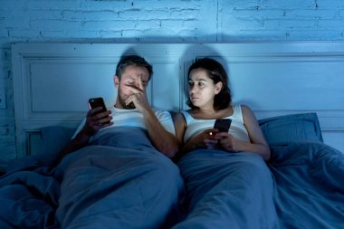 Teknoloji bağımlılığı birbirlerine ilgisizlik ve ilişki sorunları ve mobil internet bağımlılığı karanlıkta gece geç saatlerde akıllı telefonlarını kullanarak yatakta yatan öfke görmezden tarafından etkilenen çift.