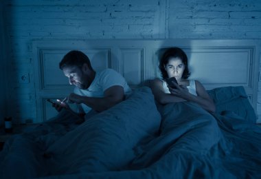 Teknoloji bağımlılığı birbirlerine ilgisizlik ve ilişki sorunları ve mobil internet bağımlılığı karanlıkta gece geç saatlerde akıllı telefonlarını kullanarak yatakta yatan öfke görmezden tarafından etkilenen çift.