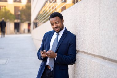 Genç adam akıllı aşınmaya üstünde hareket eden telefon açık havada city adlı metin e-posta ya da sosyal medya app sokak gönderme. Mutlu iş adamları, girişimci ve iş özgürlük iletişim teknoloji dışında çalışma.