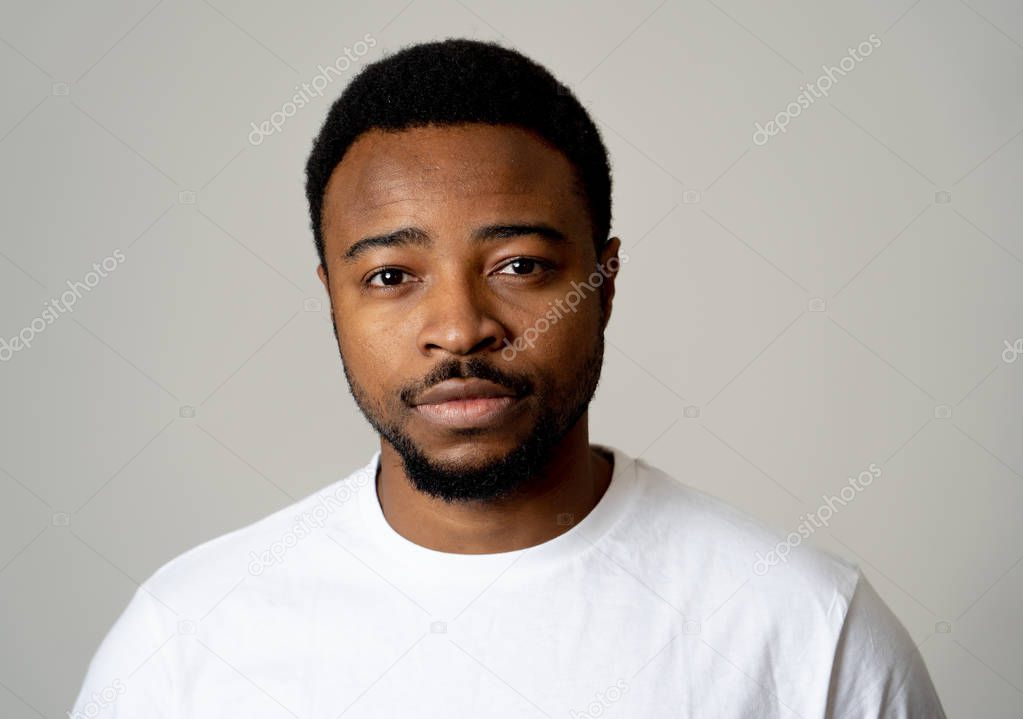 Portrait of attractive, confident african american young man looking neutral relaxed and serious in facial expressions, human emotions, Success and education concept. Isolated on grey background.