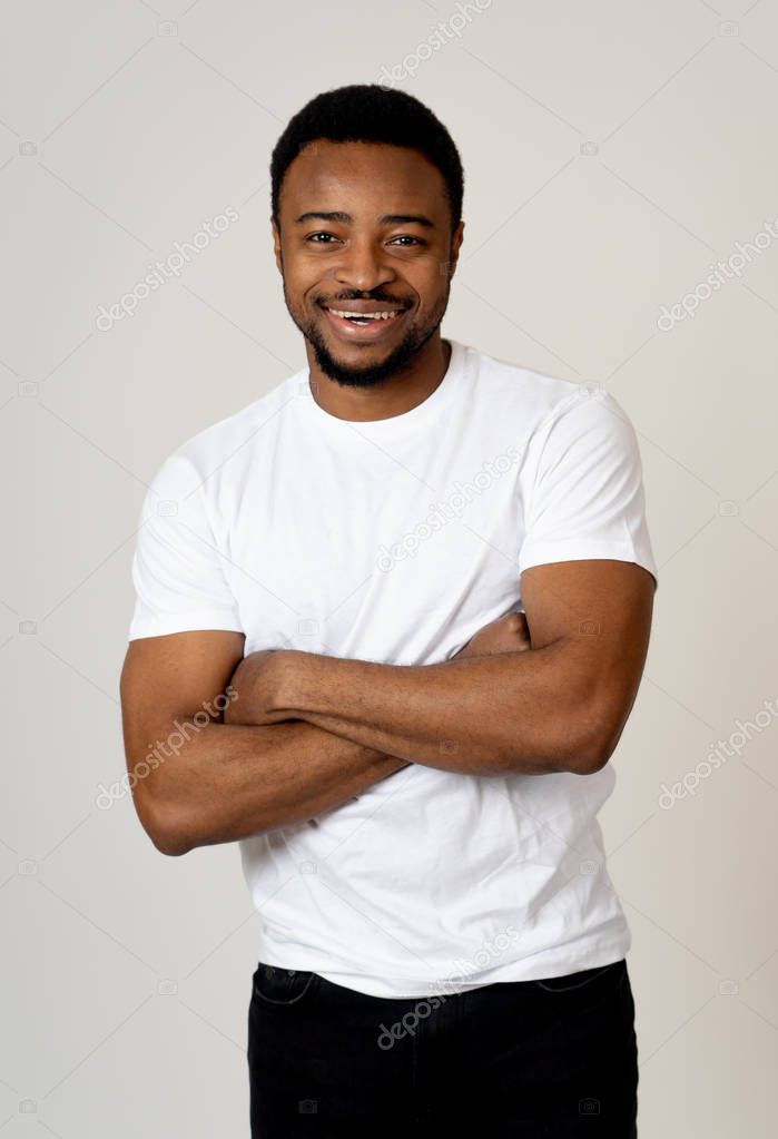 Half length portrait of attractive shy young african american man with happy face flirting with beautiful smile posing and looking at camera. People, Positive emotions and human facial expressions.