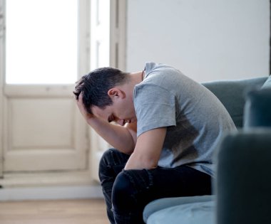Mutsuz depresif beyaz erkek ağlama ve umutsuz hissediyorum oturma odası koltukta yalan oturan vurguladı yalnız bir iş, işsizlik, anksiyete kalbi kırık ve depresyon üzüntü kavramı.
