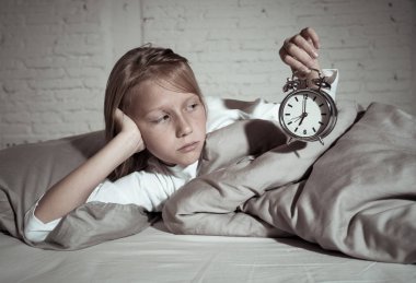 Tatlı uykusuz küçük kız yatakta alarm uyanmak zorunda ama yorgun hissetme saat uykusuz kalmak uykuda gece terörü uyku bozukluğu ve çocuk uykusuzluk kavramı sorunları bakarak üzgün yalan.